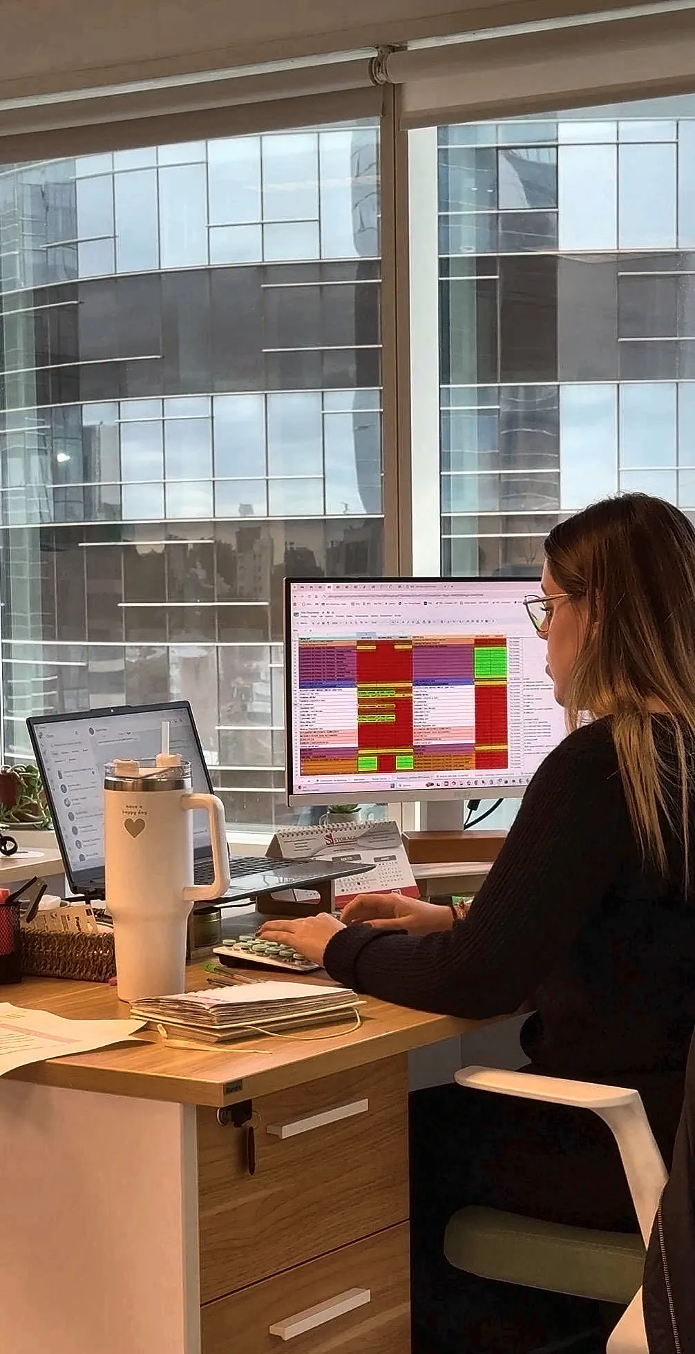 Integrante da VDC Estudio Contable trabalhando na sua mesa, com as torres do World Trade Center ao fundo